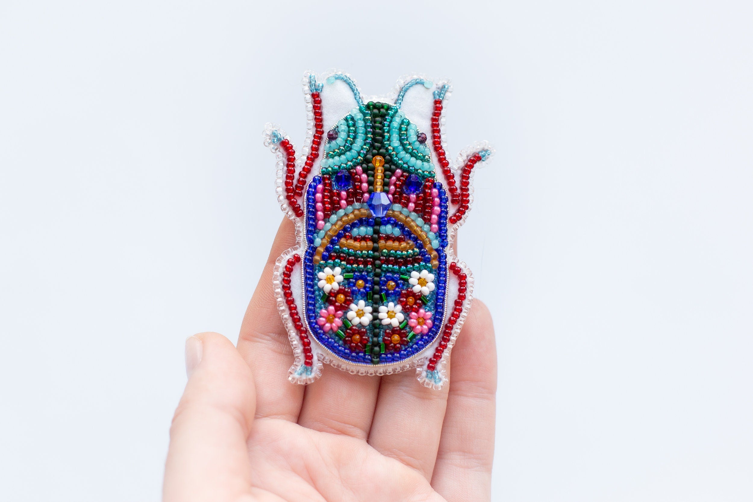 a hand holding a small beaded object in it's palm